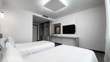 Una habitación de hotel con dos camas, un televisor de pantalla plana montado en la pared y un armario vestidor.