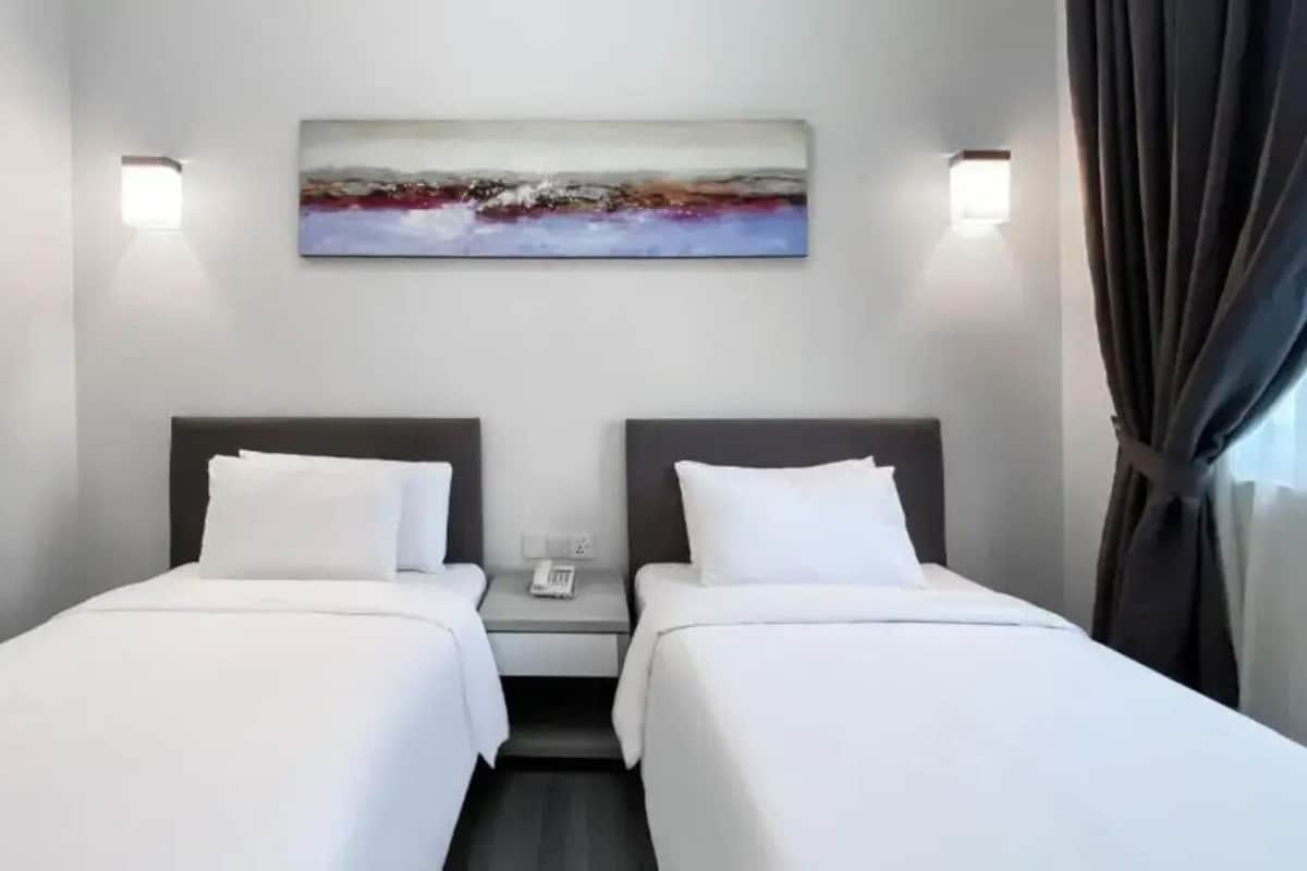 A hotel room with two beds, a painting on the wall, and a phone on the nightstand.