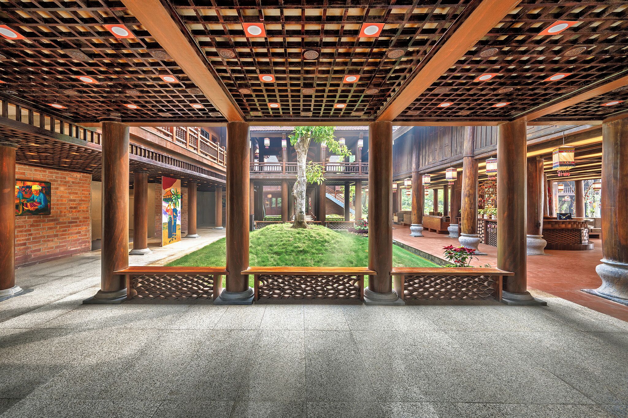 An indoor courtyard with a central lawn, wooden columns, and a covered walkway.