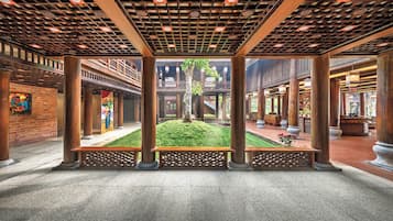 An indoor courtyard with a central lawn, wooden columns, and a covered walkway.