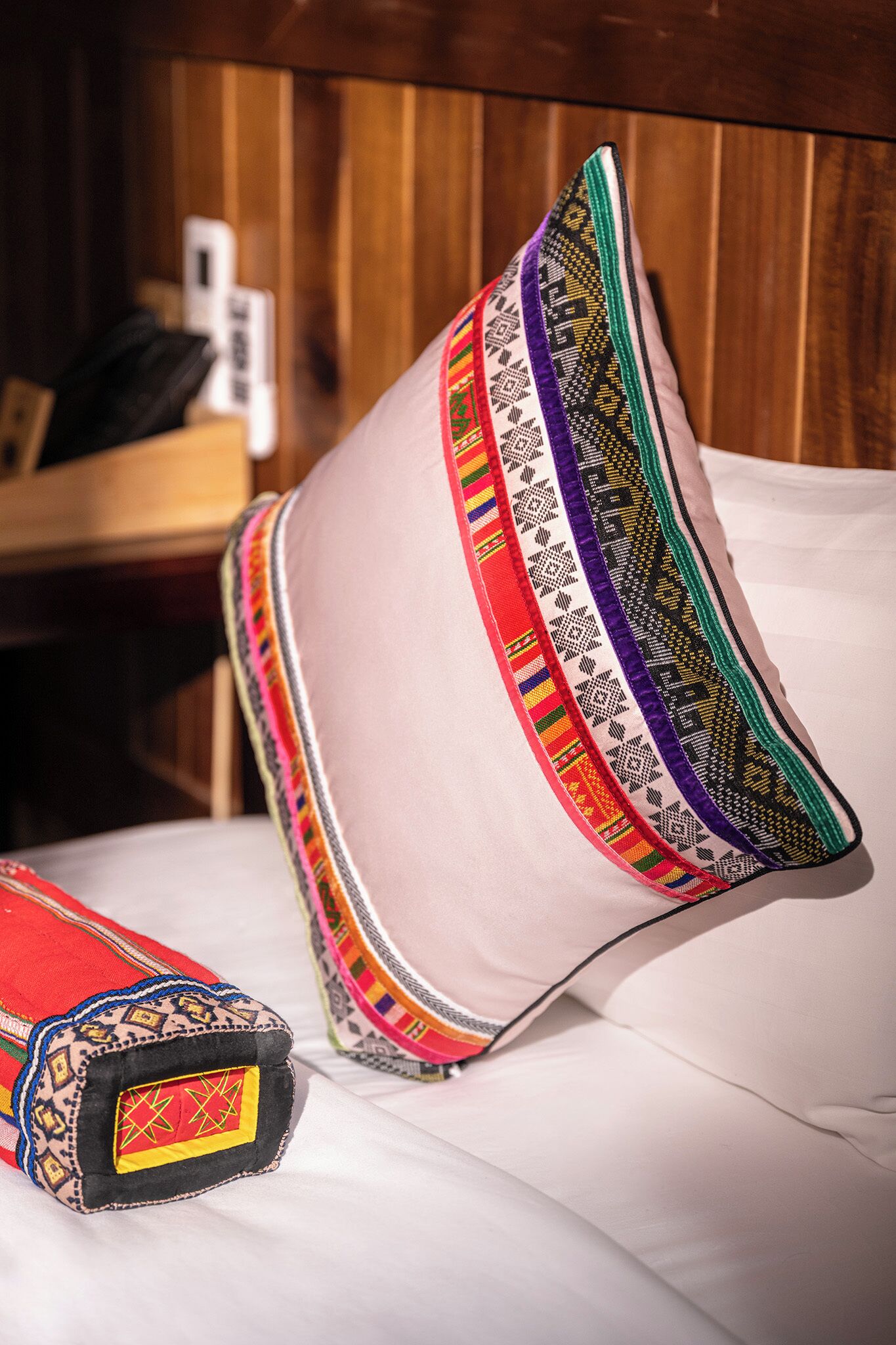 A pillow with a colorful embroidered border and a cushion with a similar design.