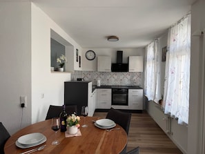 Eine moderne Küche mit eingebautem Backofen und einem Essbereich mit einem Holztisch für zwei Personen.