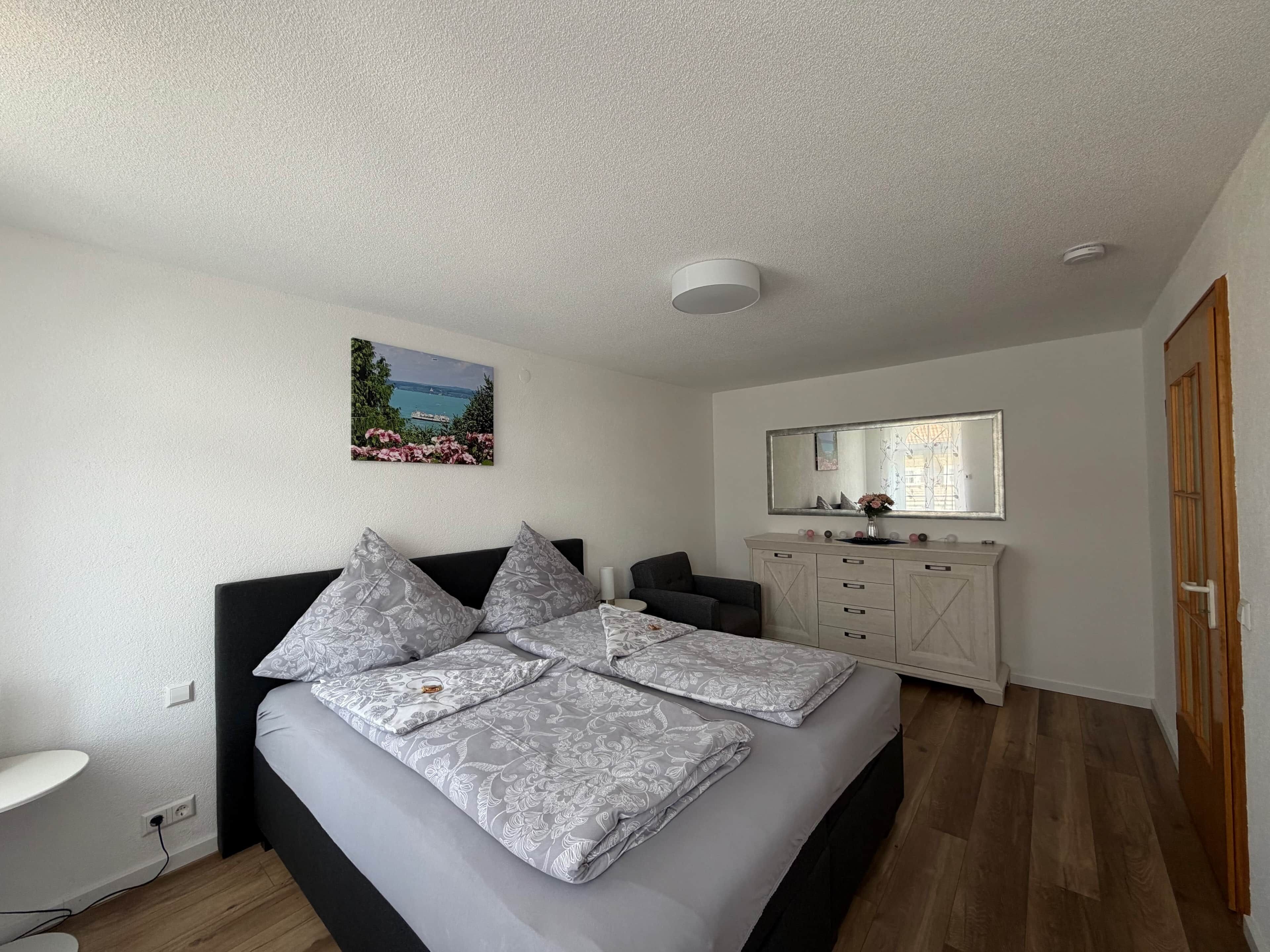 Um quarto com uma cama, penteadeira, espelho e um quadro na parede.