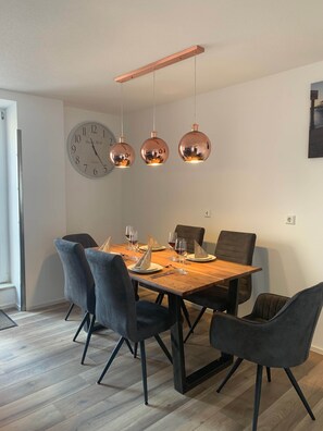 Ein Essbereich mit einem Holztisch, gedeckt für sechs Personen, sechs Stühlen und einer Wanduhr.