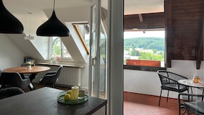 Un comedor moderno con una mesa, sillas y vistas a un paisaje verde a través de ventanas grandes.