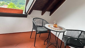 Un balcón con una mesa y dos sillas, vistas a zonas verdes y un techo de madera.
