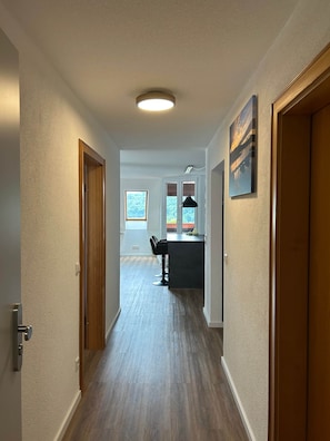 Ein Flur mit Holzboden, eine Küchenzeile mit Bar und Barhocker sowie ein Esstisch.