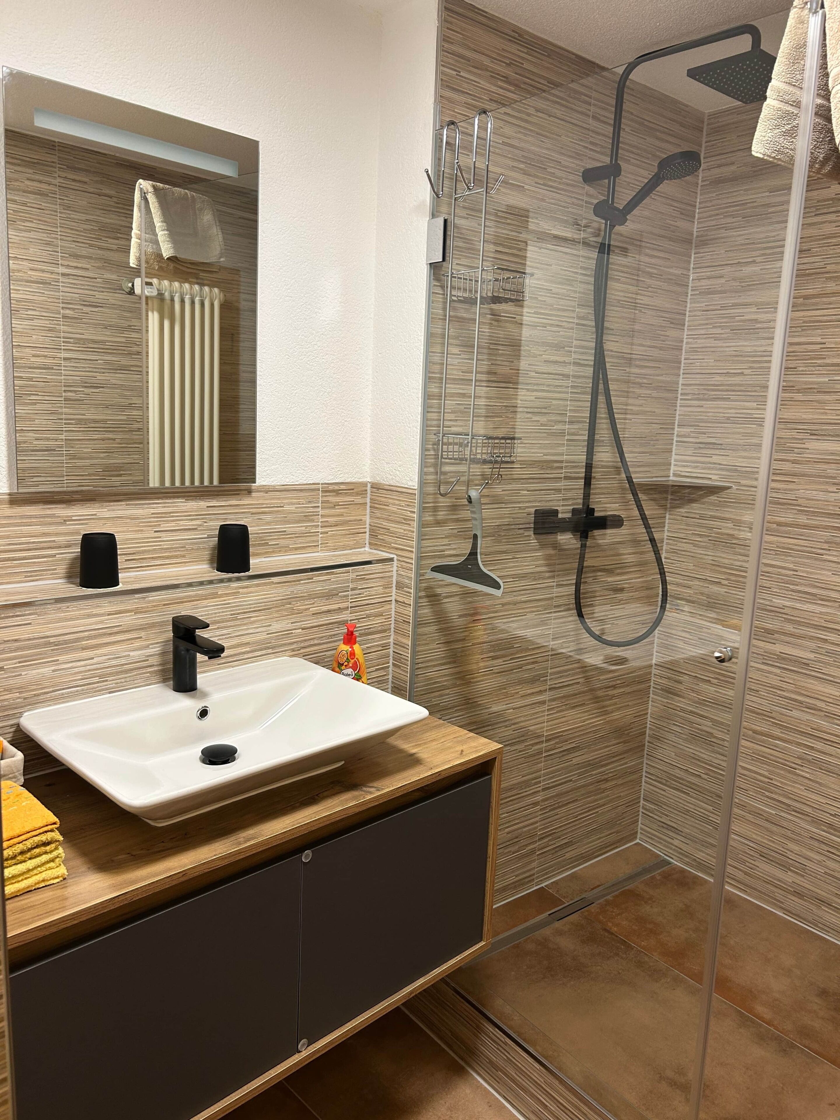 A modern bathroom with a glass-enclosed shower, a white sink, and a mirror above it.