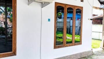 A building with a white exterior, a large air conditioning unit mounted on the wall, and a wooden door.