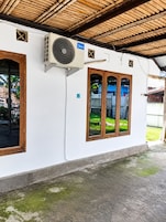 Un edificio con fachada blanca, un equipo de aire acondicionado grande montado en la pared y una puerta de madera.