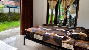 Ein Schlafzimmer mit Bett, Vorhängen, einer Schiebetür aus Glas und Blick ins Freie.