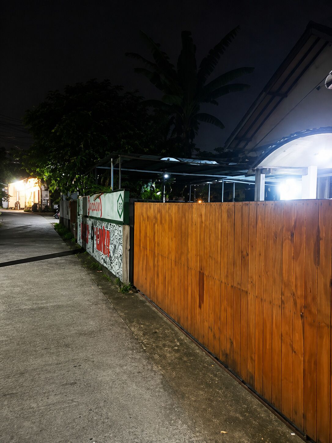 Una entrada protegida por un muro de madera y una pared con grafitis.