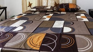 Ein Hotelzimmer mit einem Bett, einem Nachttisch, einer Klimaanlage und Vorhängen mit Schmetterlingsmotiven.