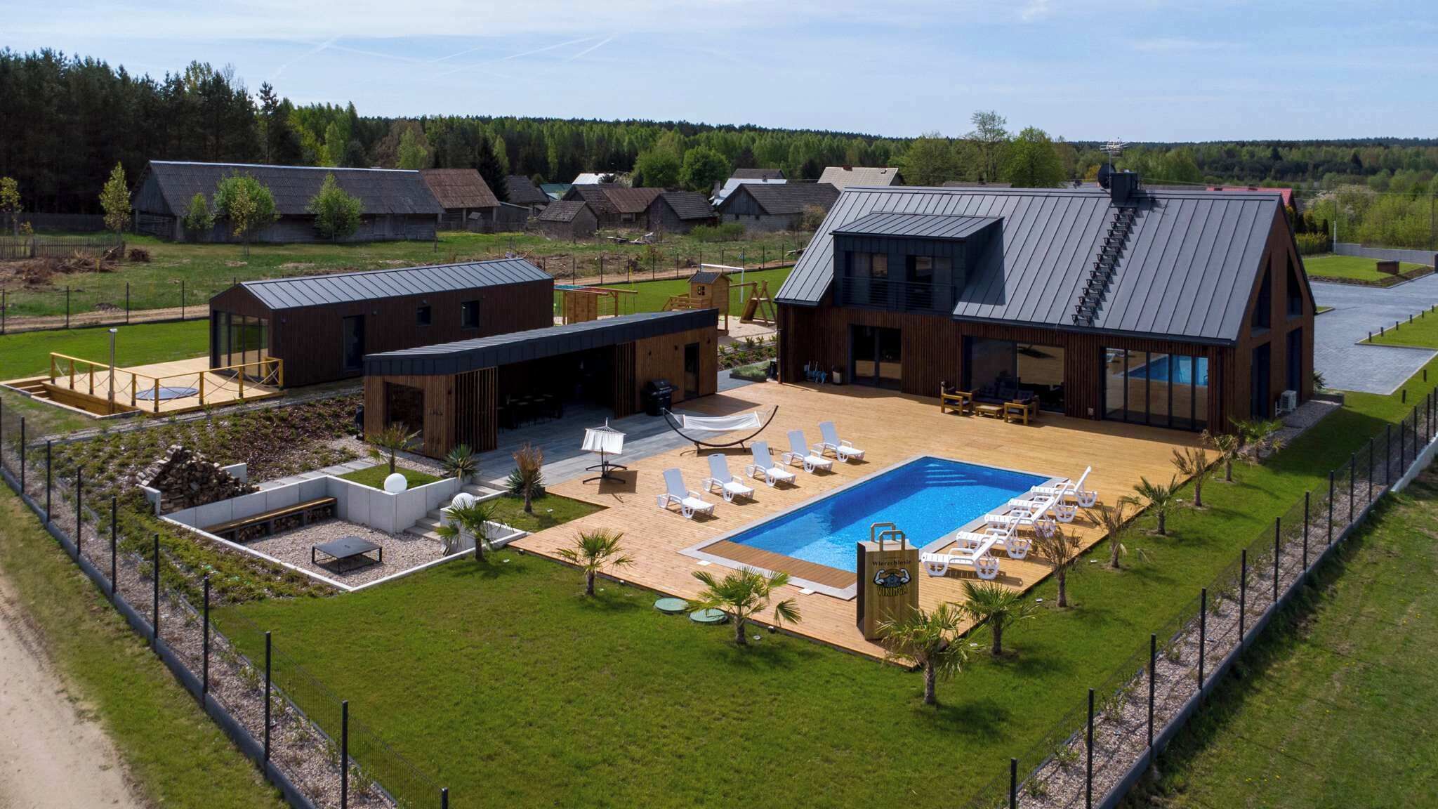Ein modernes Haus mit großem Pool, Sitzgelegenheiten im Freien und einem gepflegten Rasen.