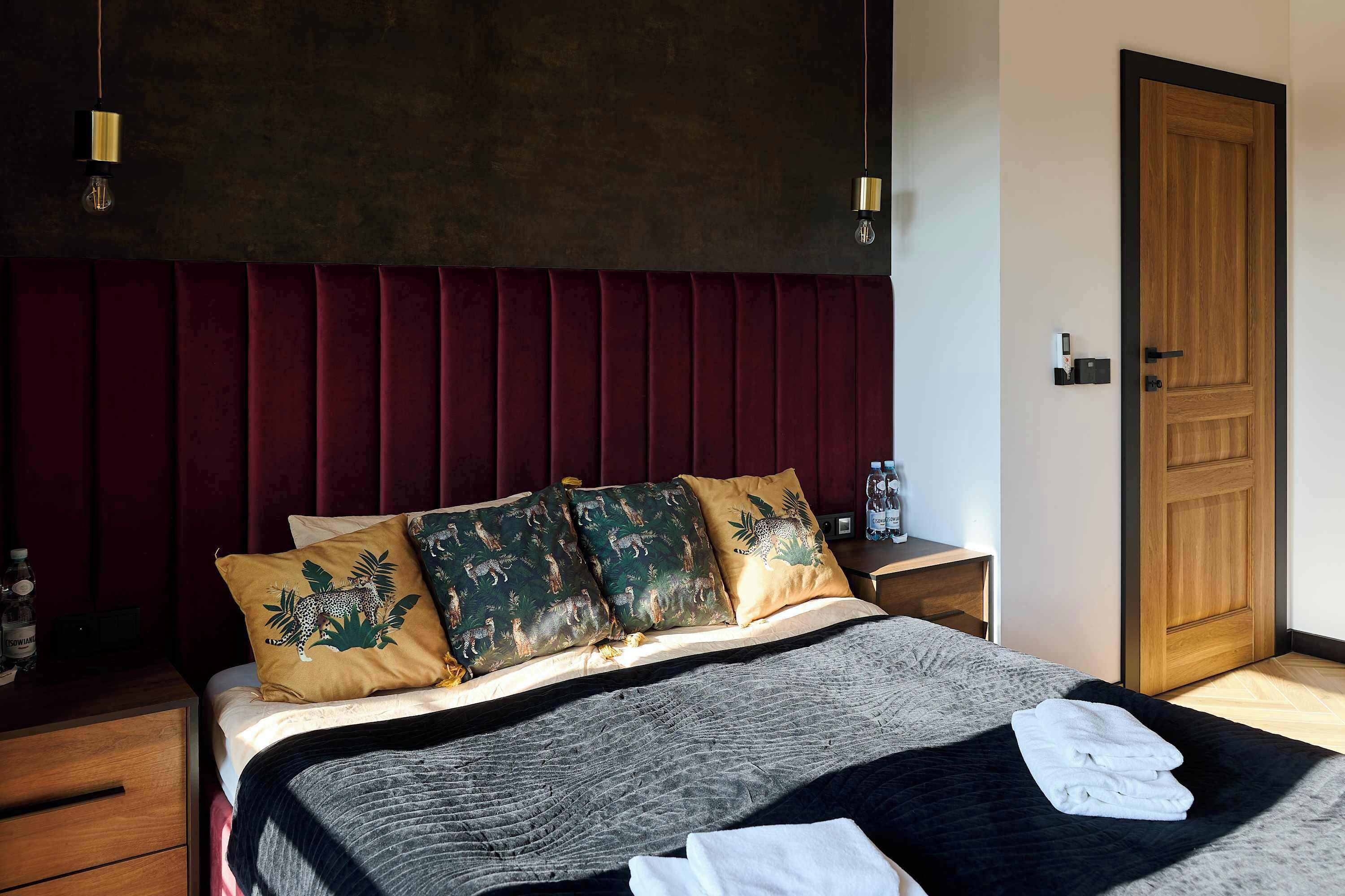 A hotel room with a large bed, a wooden door, and a nightstand with a water bottle.