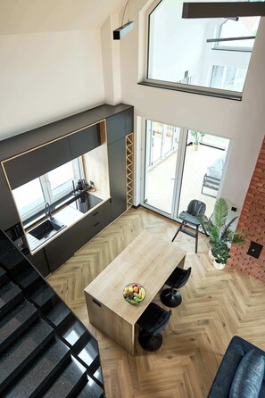 A modern kitchen with a built-in oven, a dining area with a herringbone floor, and a large window offering a view of the outdoors.