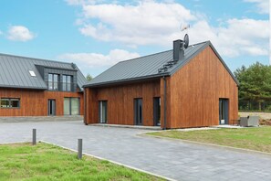 A modern building with a sloped roof, large windows, and a wooden facade.