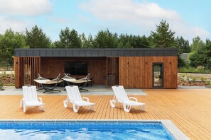 A modern outdoor pool area with lounge chairs and a wooden deck.