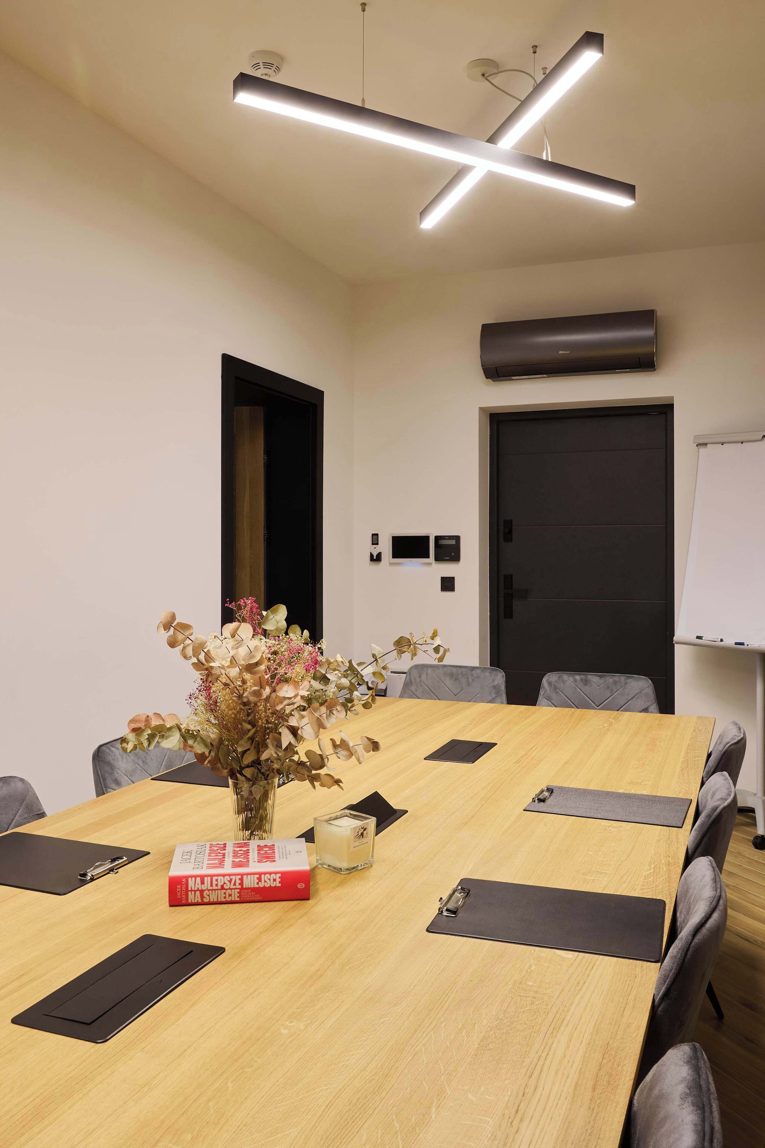 A conference room with a long table, chairs, a whiteboard, and a wall-mounted air conditioner.