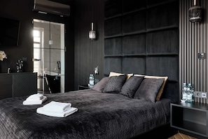 A modern bedroom with a large bed, a bedside table, a mirror, and a nightstand.