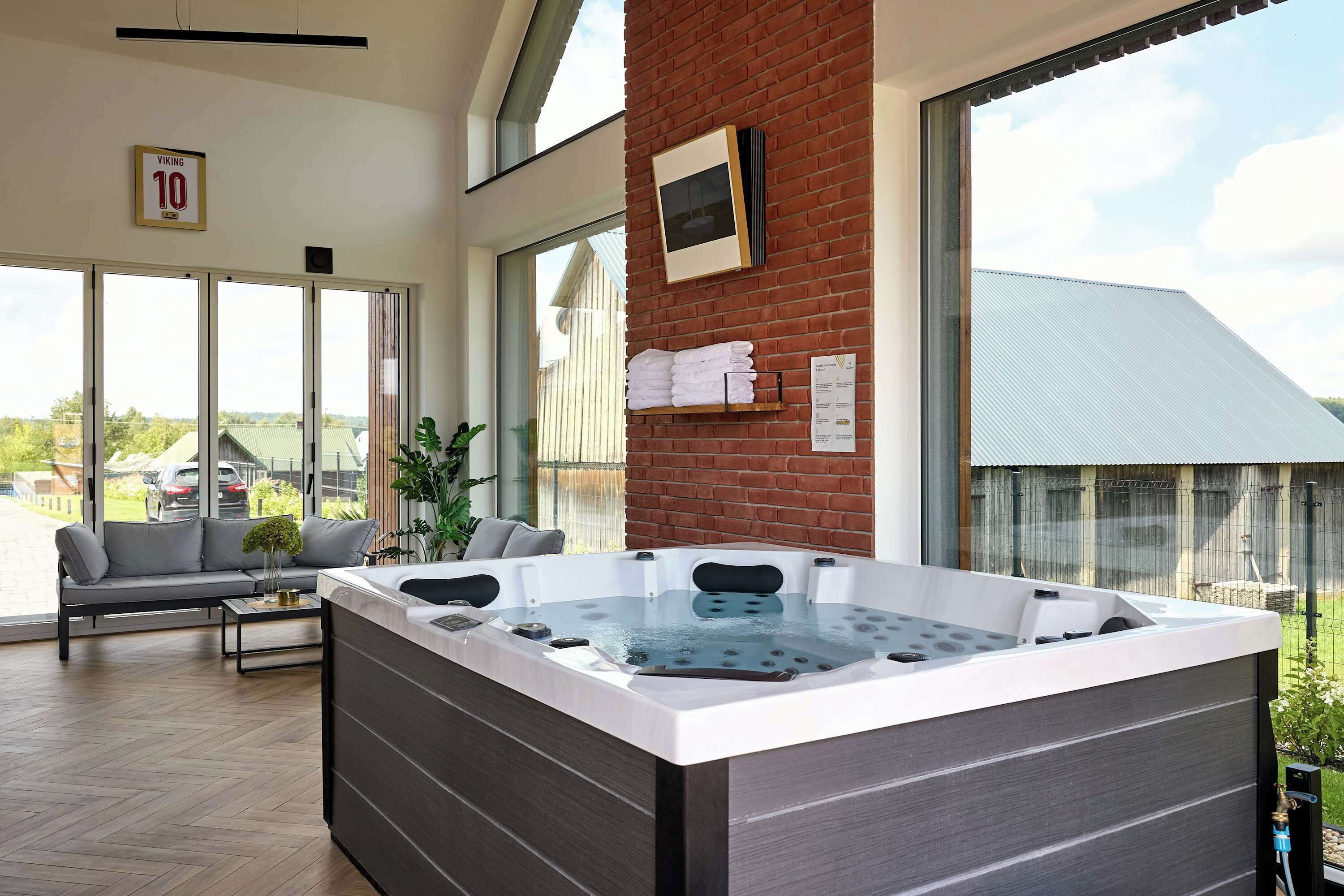 Een moderne spa-ruimte met een whirlpool, zitplaatsen en grote ramen.