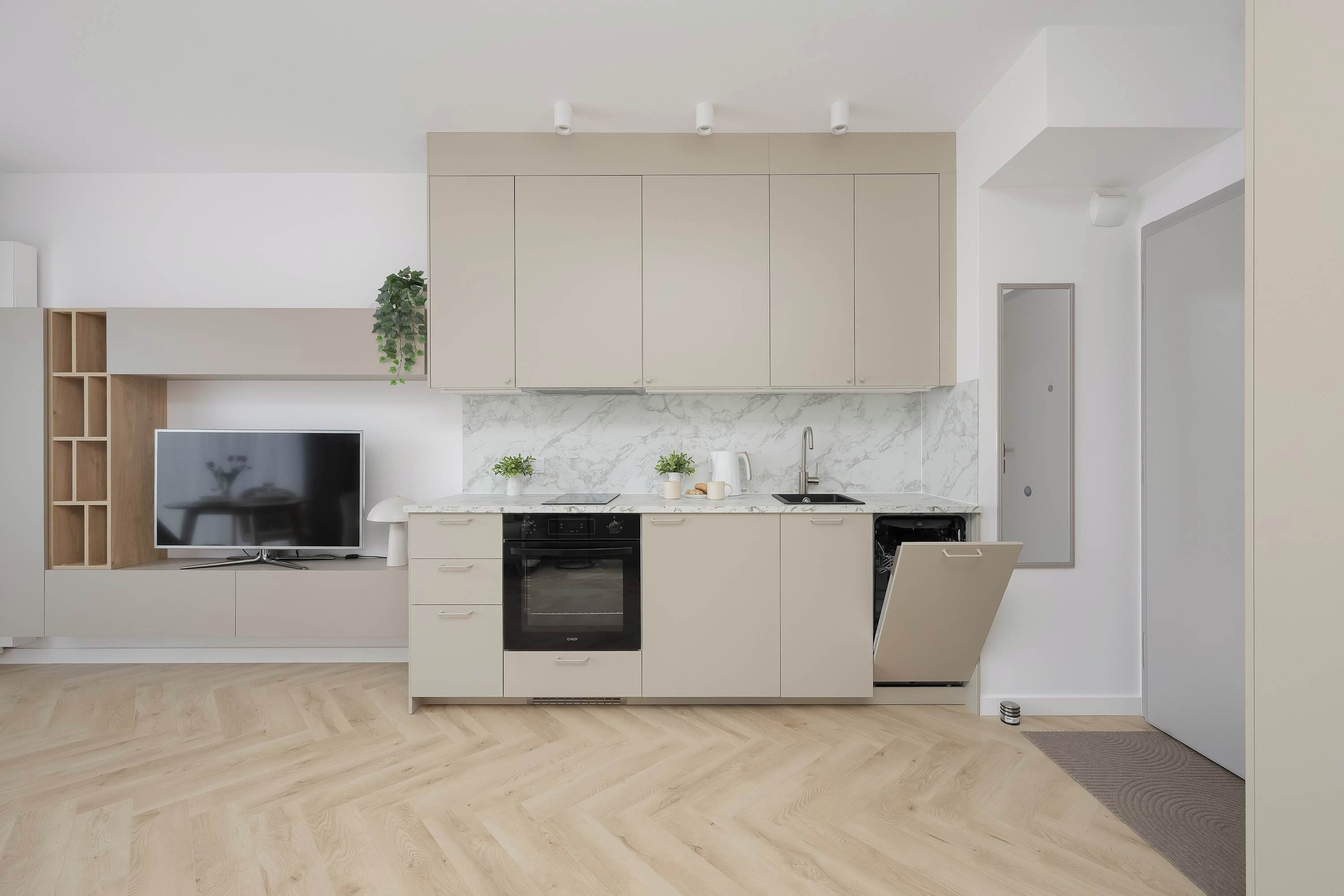A modern kitchen with a built-in oven, a television, and a small island with a sink and countertop.