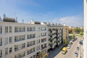 Ein mehrstöckiges Wohnhaus mit Balkonen, Straßenszene und geparkten Autos.