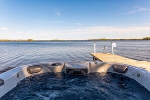 Ein Boot mit Whirlpool im Vordergrund und einer anlegenden Plattform, die sich in ruhiges Wasser erstreckt.