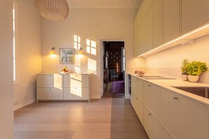 A modern kitchen with a central island, pendant lighting, and a view into another room. - Stay North - Annala. (Pispala)