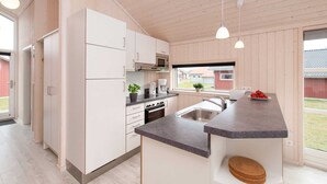 Eine moderne Küche mit weißen Schränken, einem Backofen, einer Spüle und Pendelleuchten.