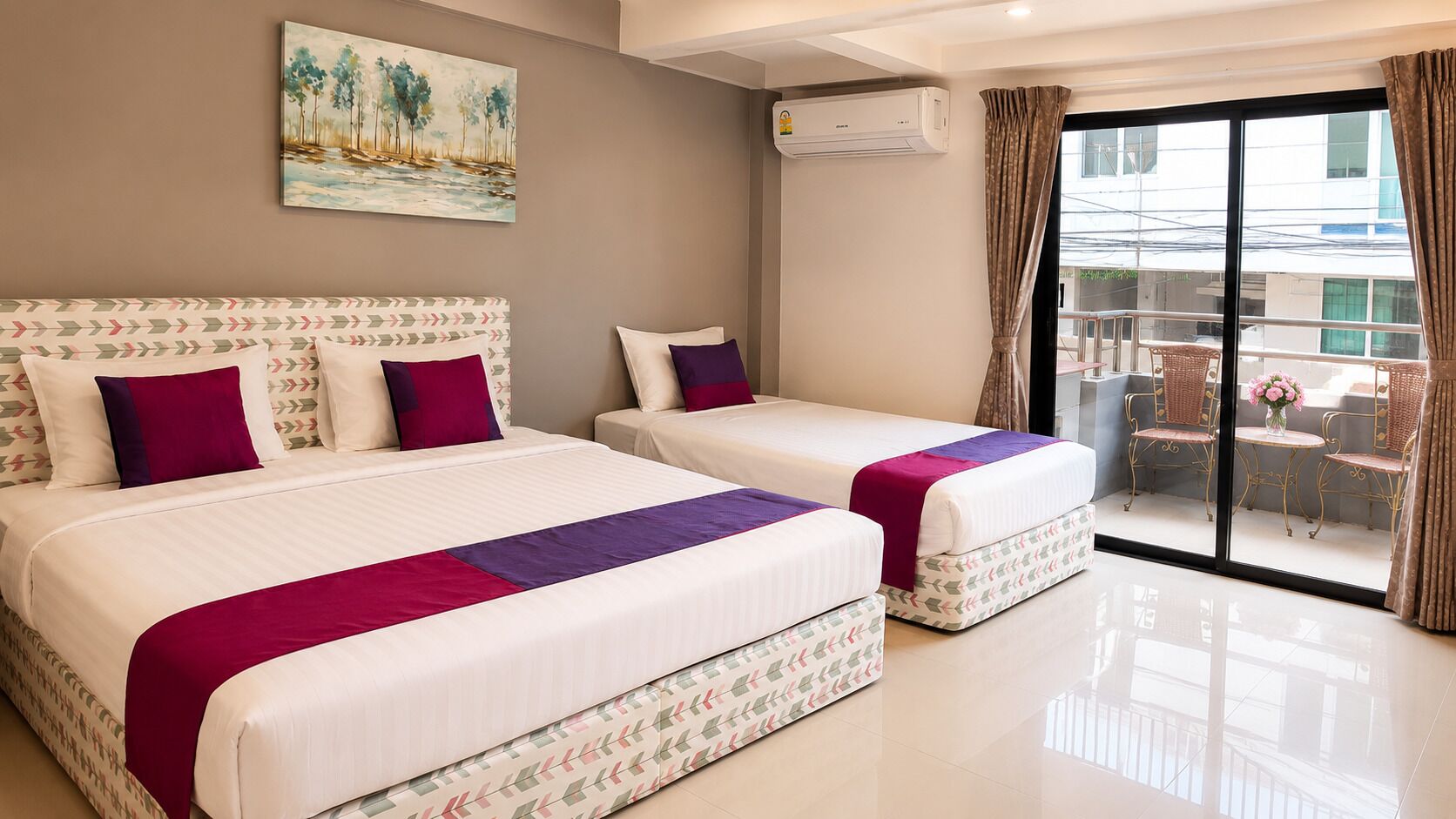 A hotel room with two beds, a balcony with wicker furniture, and a painting on the wall.