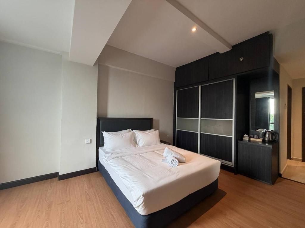 Quarto de hotel moderno com uma cama grande, um guarda-roupa com portas de correr e uma pequena área de kitchenette.