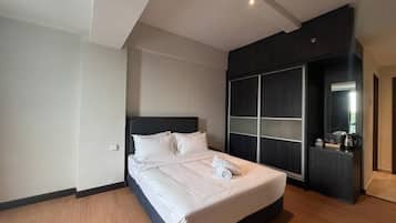 Quarto de hotel moderno com uma cama grande, um guarda-roupa com portas de correr e uma pequena área de kitchenette.