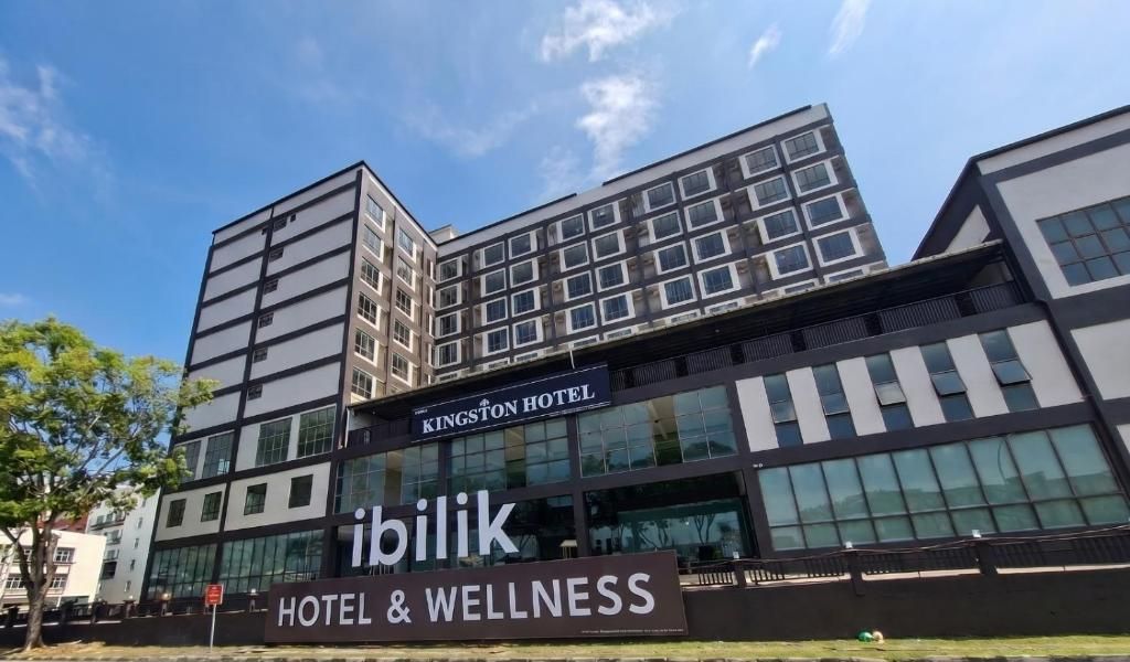 A modern hotel building with a sign for 'Kingston Hotel' and 'Ibilik Hotel & Wellness'.