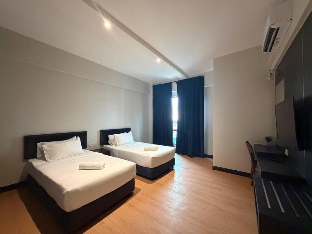 A hotel room with two beds, a desk, and a TV.