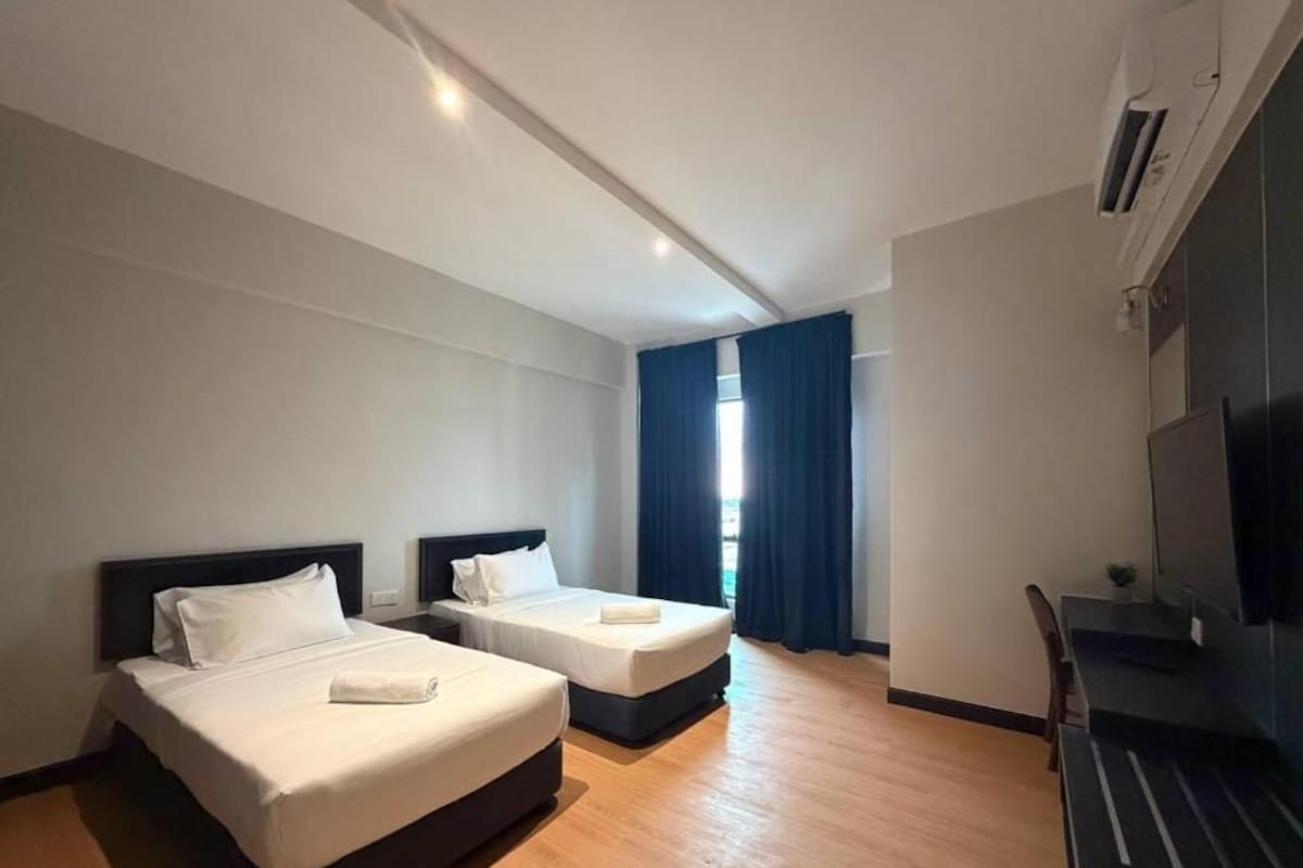 Quarto de hotel com duas camas, uma escrivaninha e uma televisão.