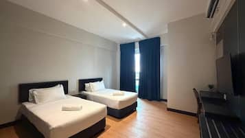 A hotel room with two beds, a desk, and a TV.