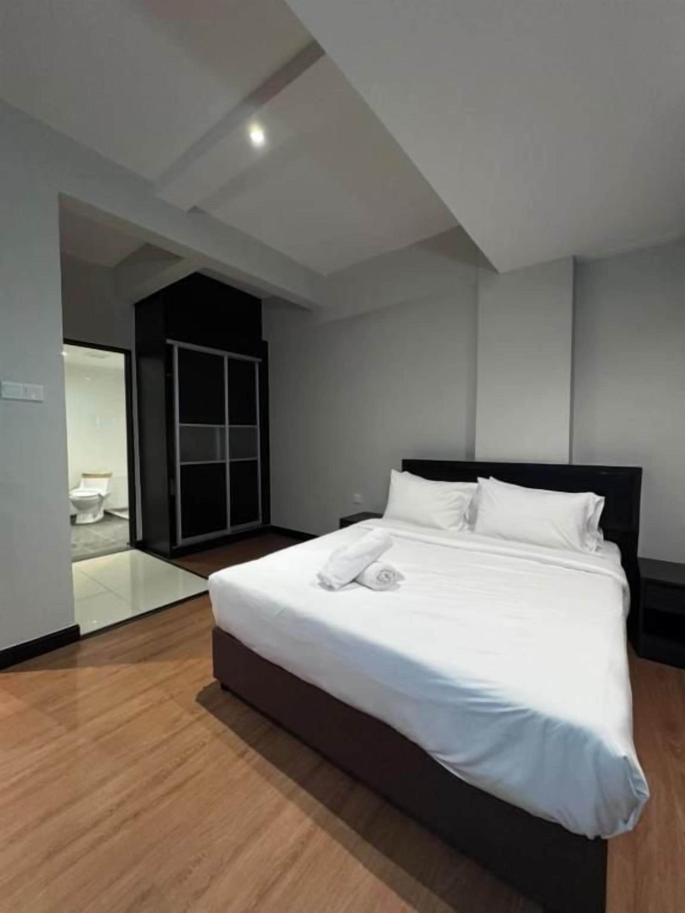 A modern hotel room with a large bed, a separate bathroom, and a view of the outside.