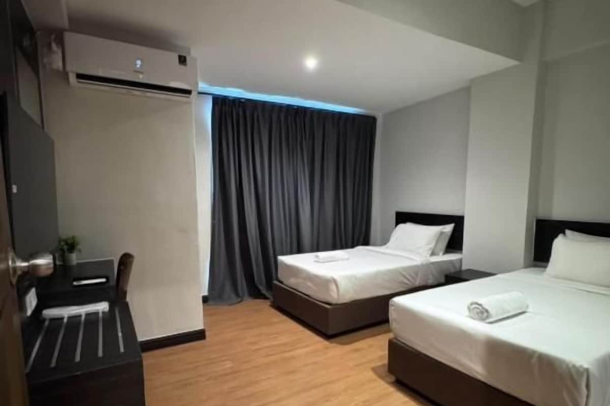 Ett hotellrum med två sängar, ett skrivbord och en luftkonditioneringsanläggning.