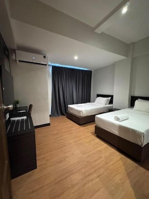 Ett hotellrum med två sängar, ett skrivbord och en luftkonditioneringsanläggning.