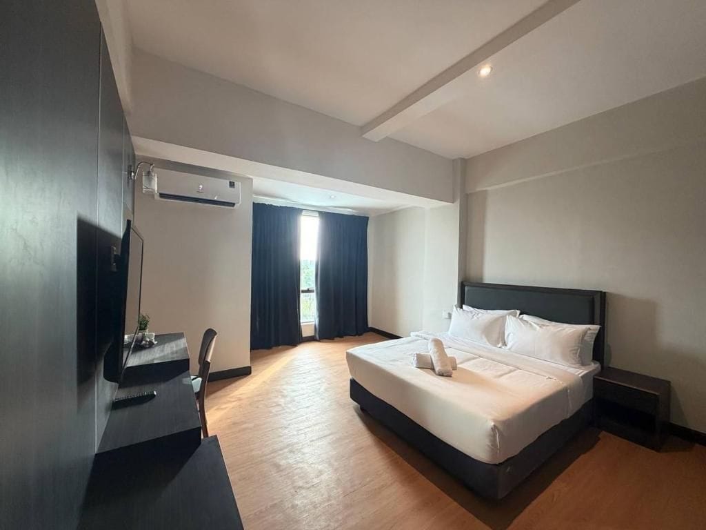 A hotel room with a bed, a desk, and a television.