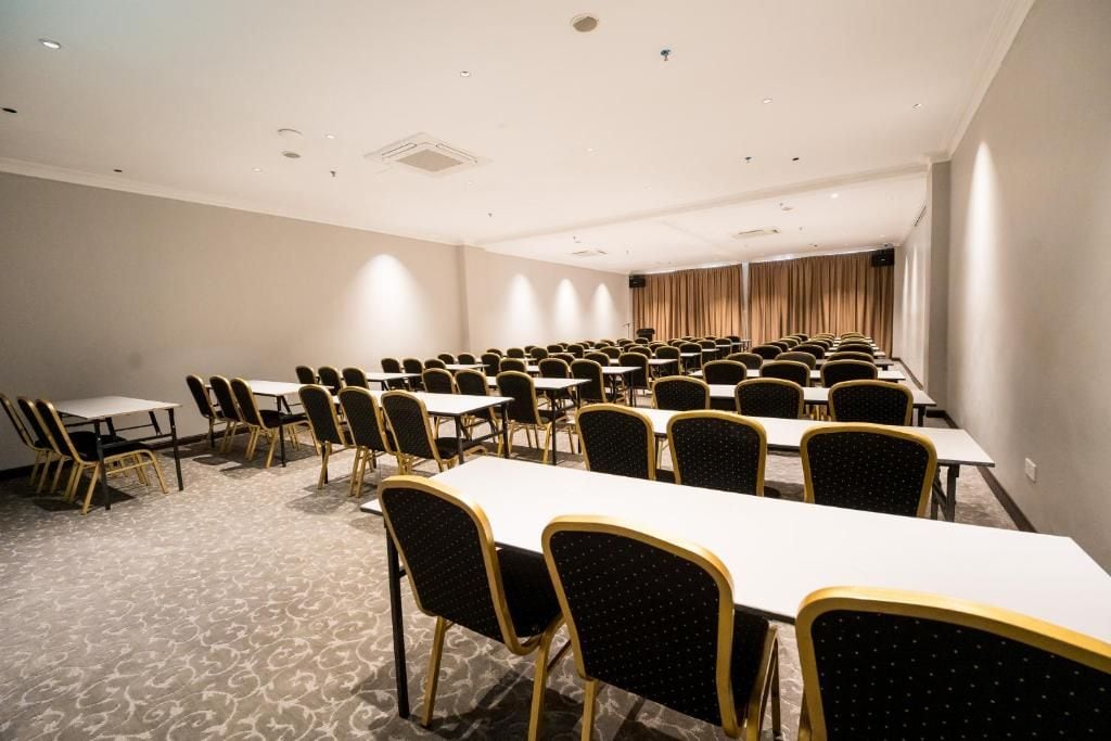 A conference room with rows of tables and chairs, carpeted floor, and a curtain backdrop.