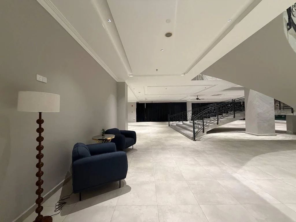 A spacious interior with a modern staircase, a seating area with sofas, and a floor lamp.