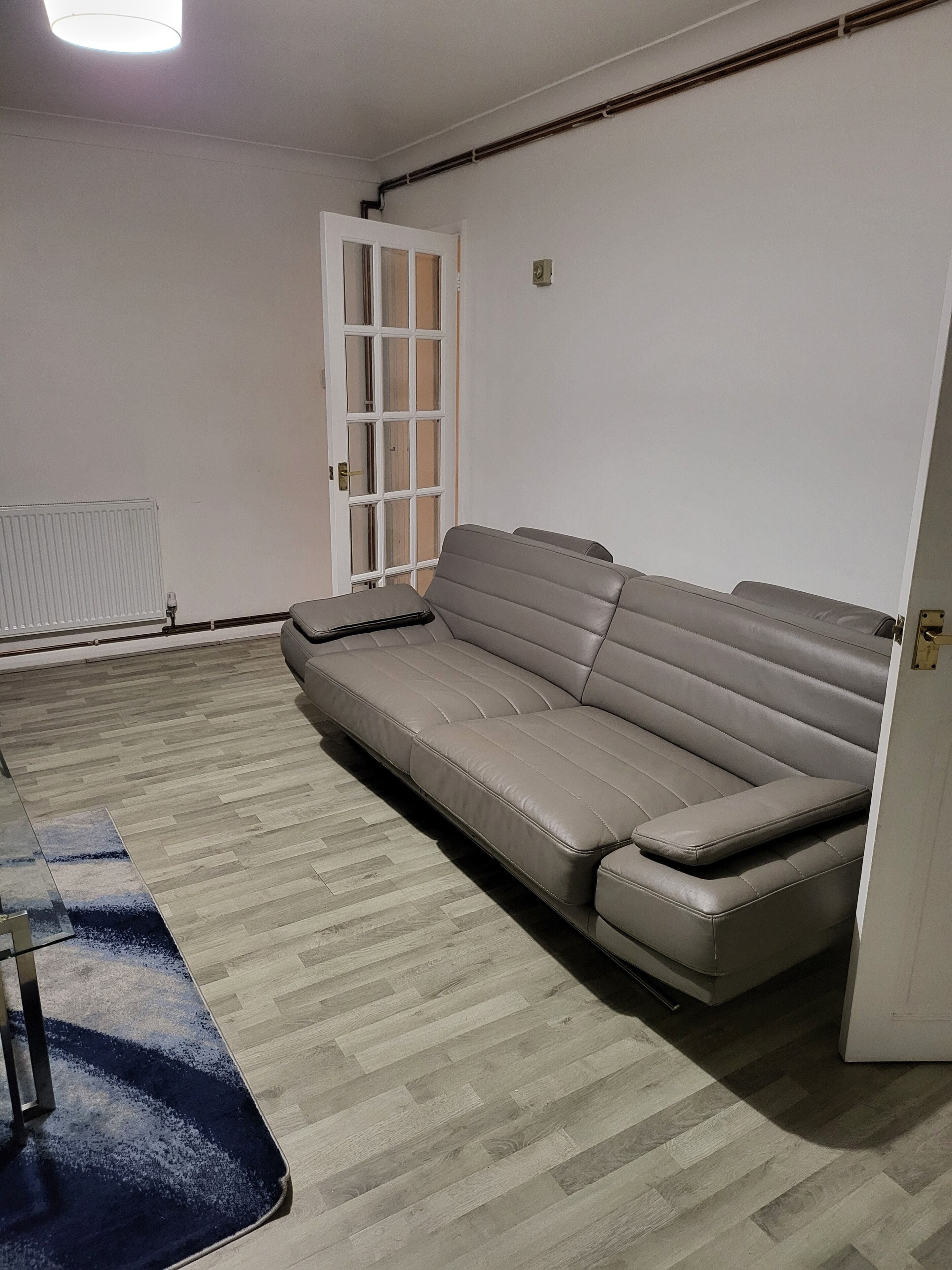 A room with a sofa, a radiator, and a door.