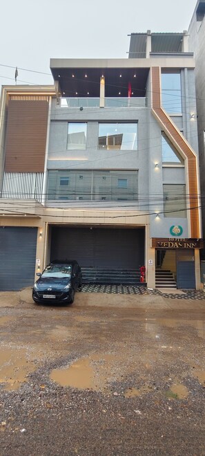 A modern hotel with a two-story structure, a covered parking area, and a visible entrance. - Hotel Vedas Inn (Gwalior)