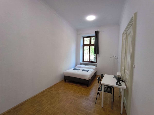 A small, single-room accommodation with a bed, a table, and a chair. - Fantastic Inn Kraków - B7 (Kraków)