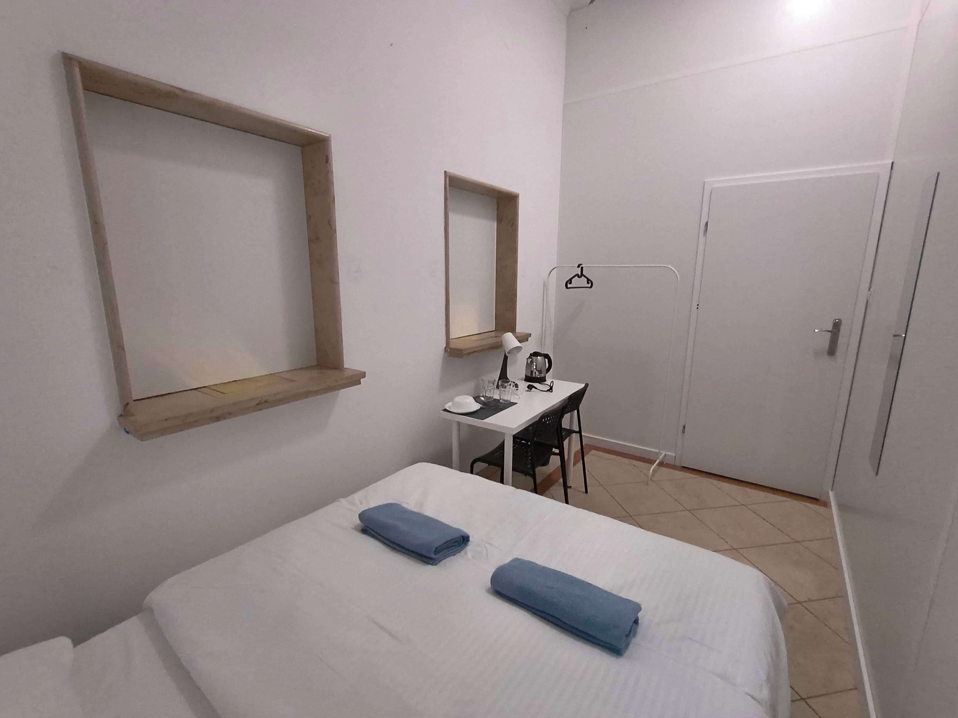 Un dormitorio con cama, escritorio, silla, espejo y armario.