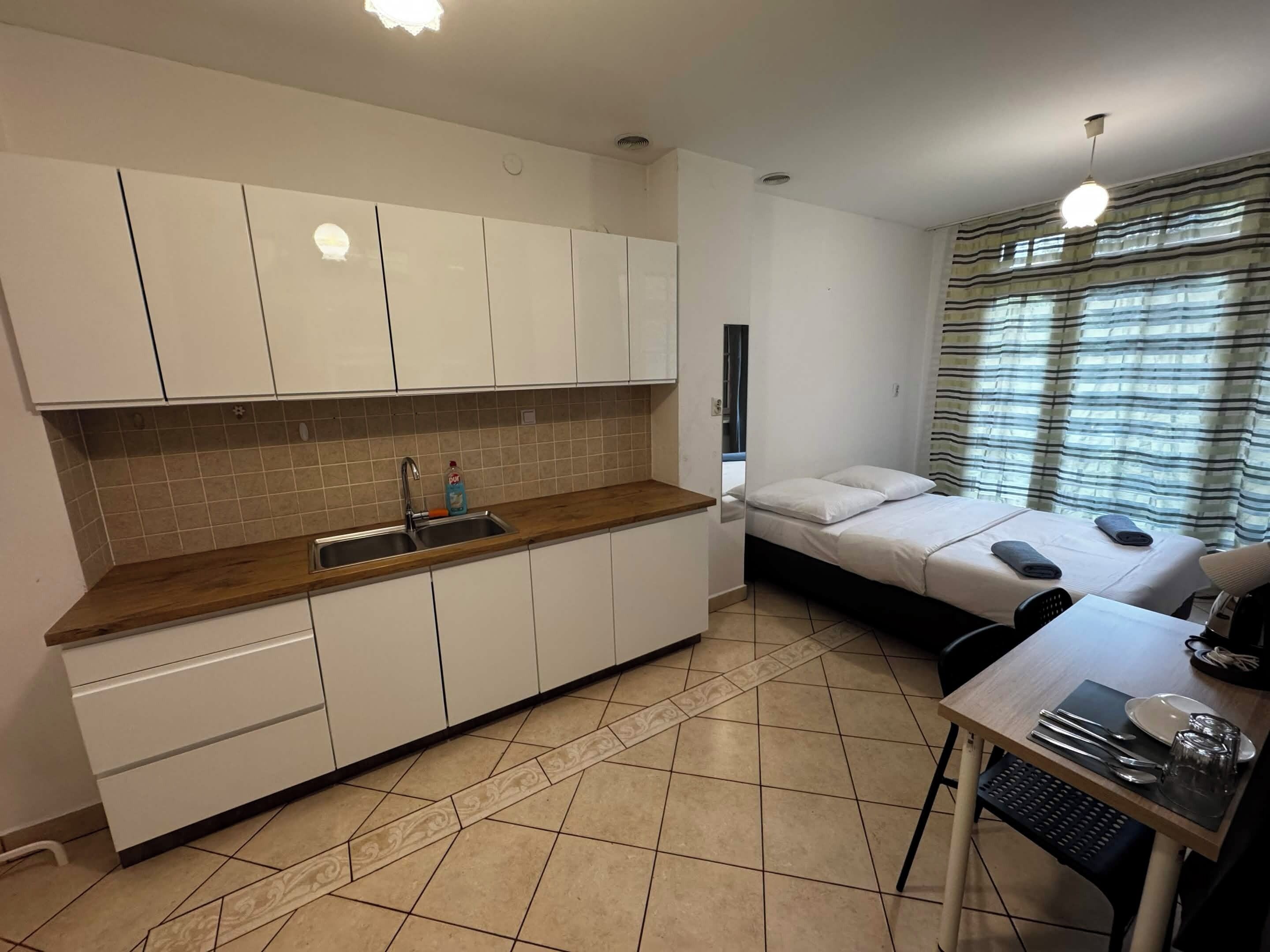 Una habitación pequeña con kitchenette, cama y comedor.