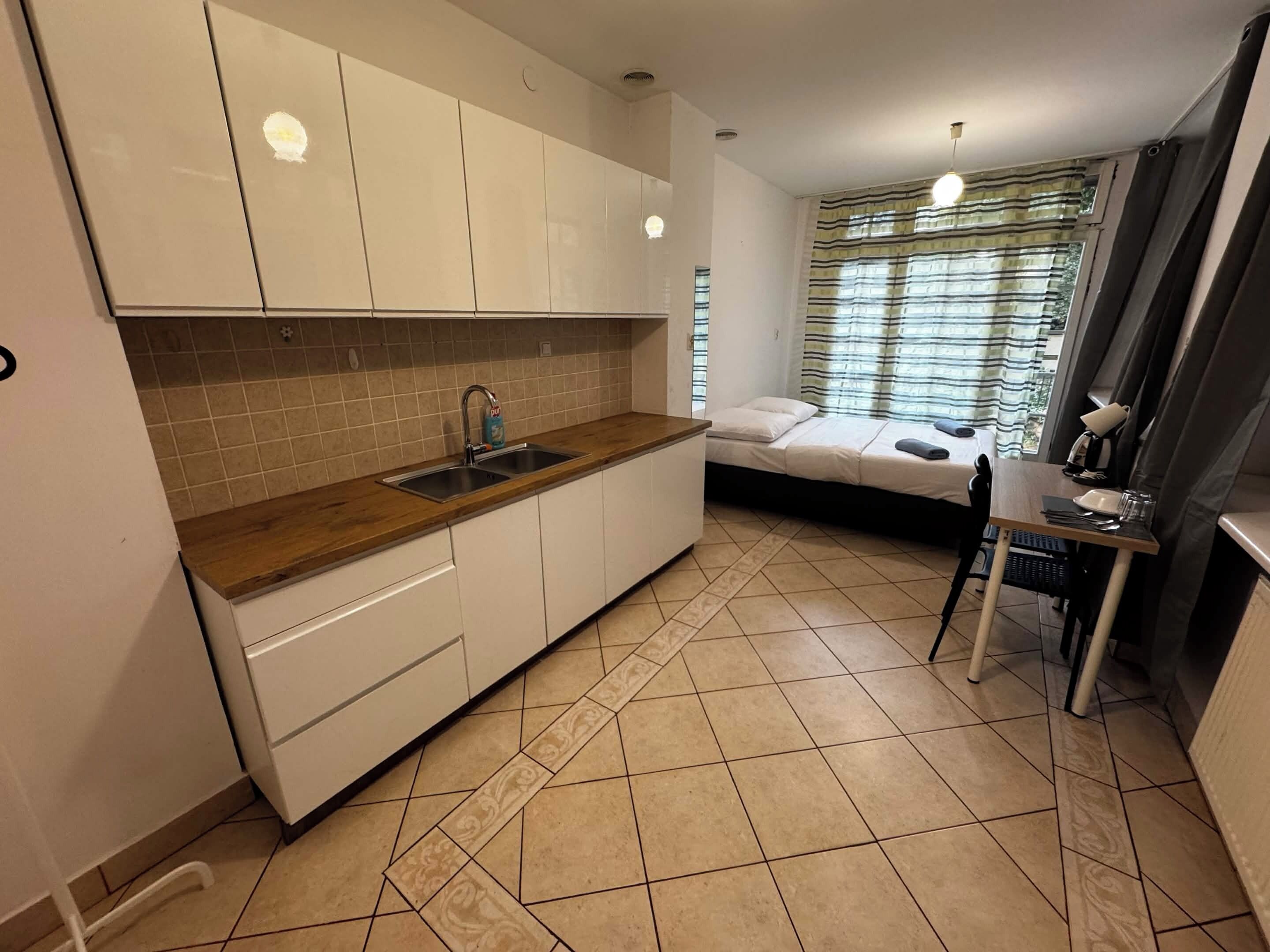 A compact kitchen with a sink, cabinets, and a dining area with a table and chairs.