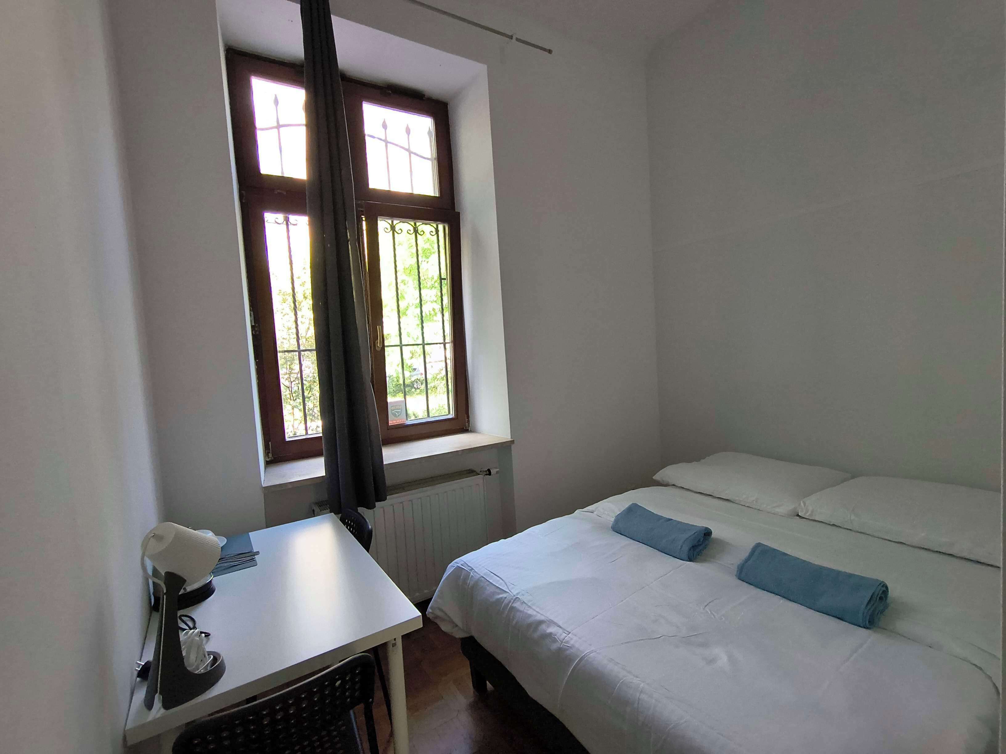 Una stanza con un letto, una scrivania e una finestra con tende.